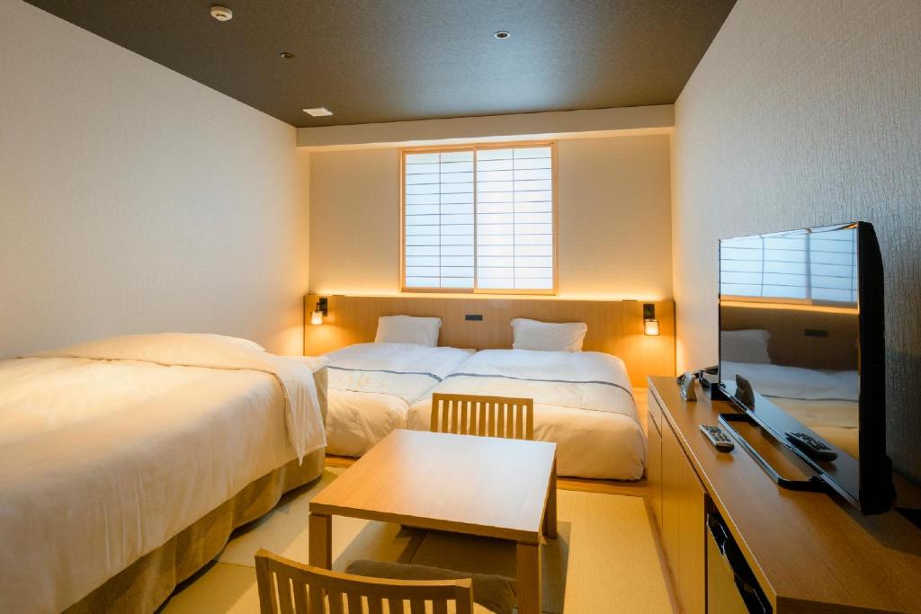 a hotel room with two beds and a desk and a table at Tosei Hotel Cocone Kamakura in Kamakura