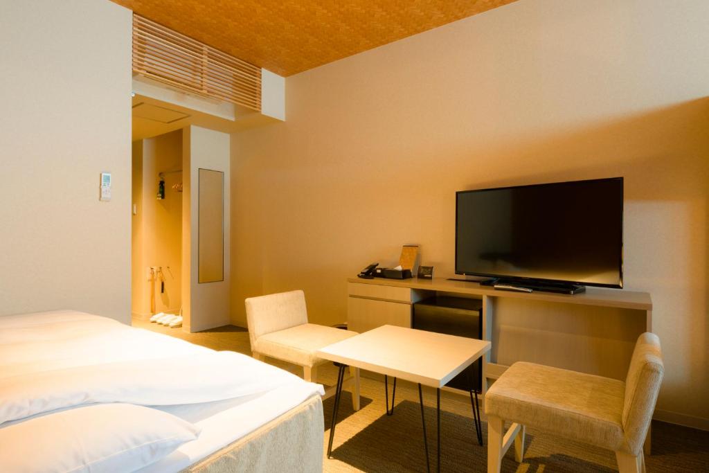 a bedroom with a bed and a desk with a television at Tosei Hotel Cocone Kamakura in Kamakura