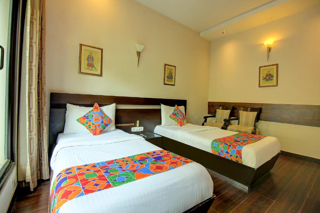 a hotel room with two beds and a chair at FabHotel Phoenix Hospitality in Gurgaon