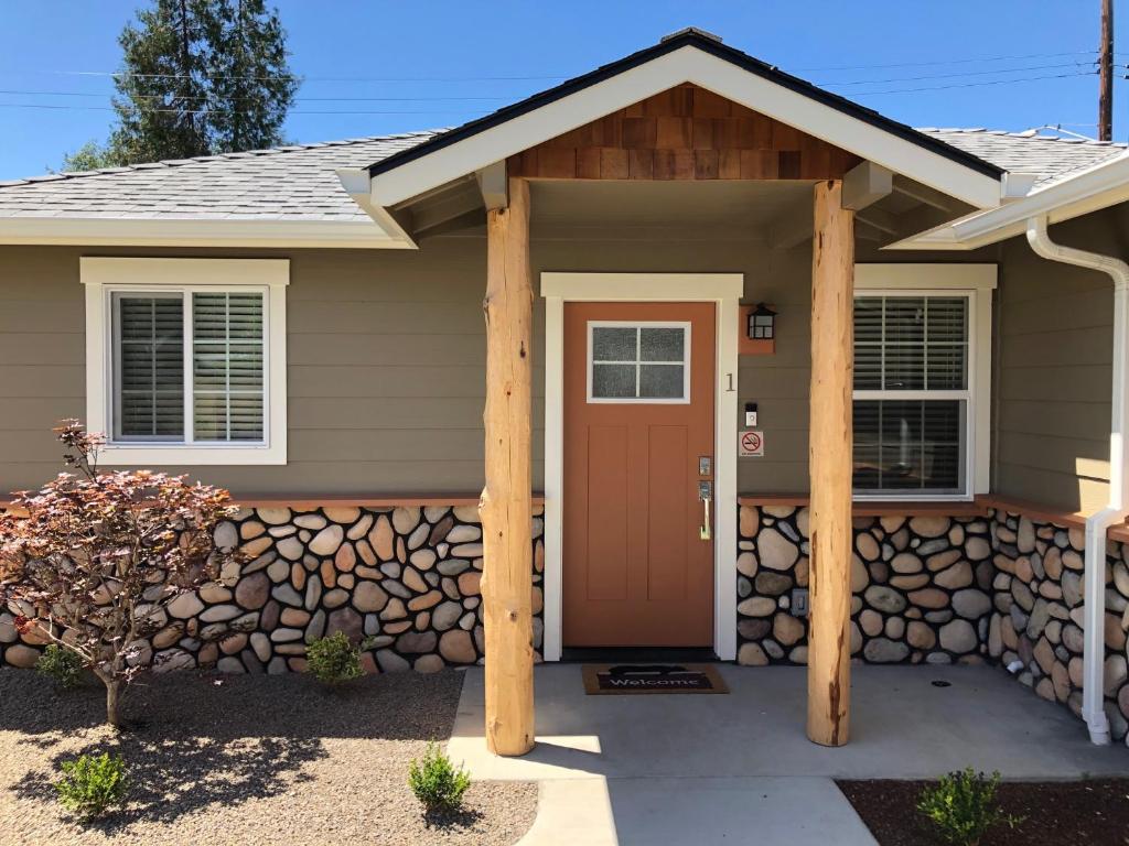 a house with a brown door and a stone wall at Riverside Cabin 1 in Grants Pass