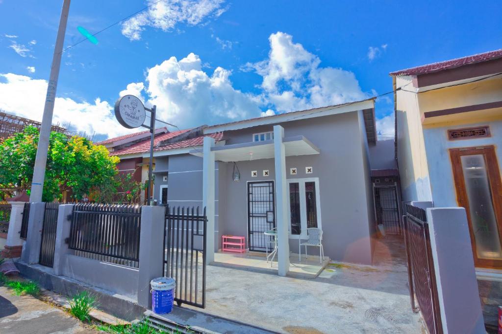 a small white house with a fence at OMAMAE HOMESTAY PAGARALAM in Pagaralam