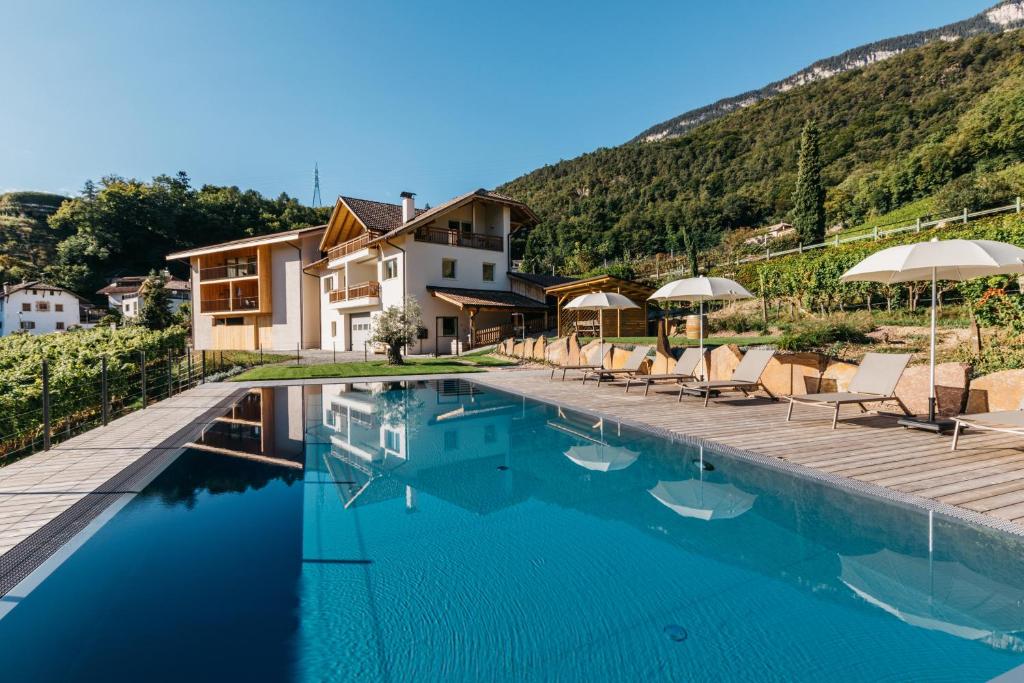 einen Pool mit Stühlen und Sonnenschirmen neben einem Haus in der Unterkunft Egarter in Appiano sulla Strada del Vino