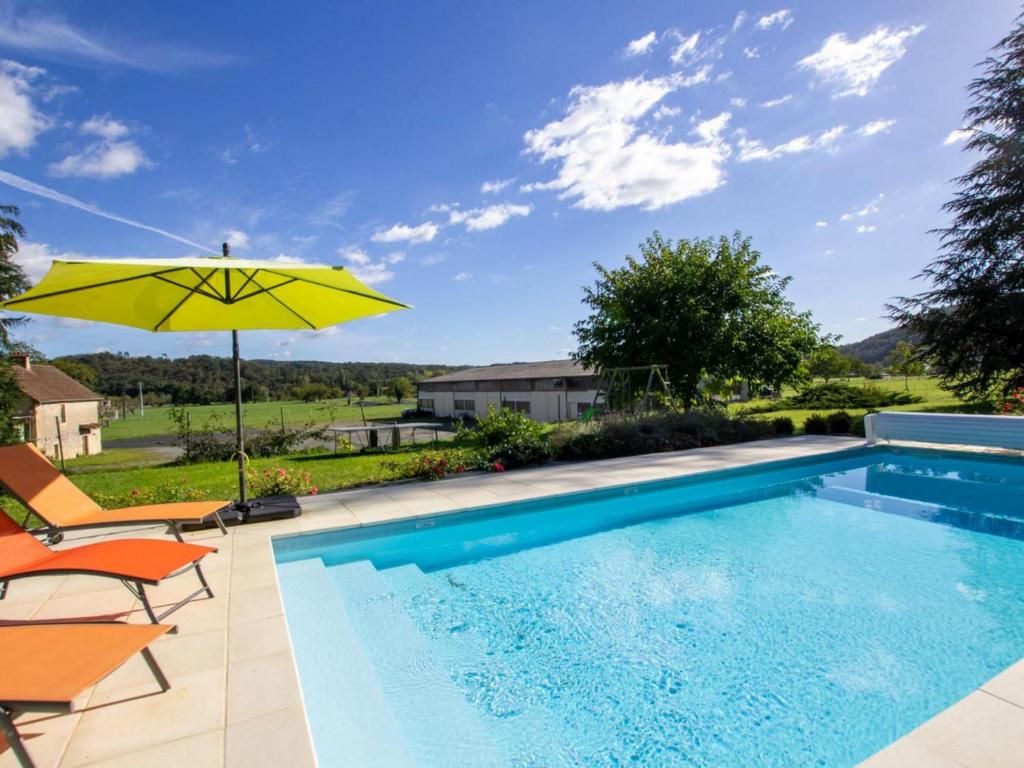 a swimming pool with a yellow umbrella and chairs at Gîte Montignac, 4 pièces, 6 personnes - FR-1-616-83 in Montignac