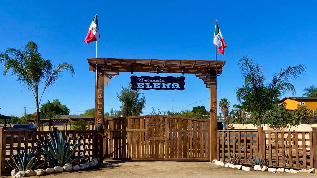 a wooden gate with a sign and two flags at Estancita Elena in Valle de Guadalupe
