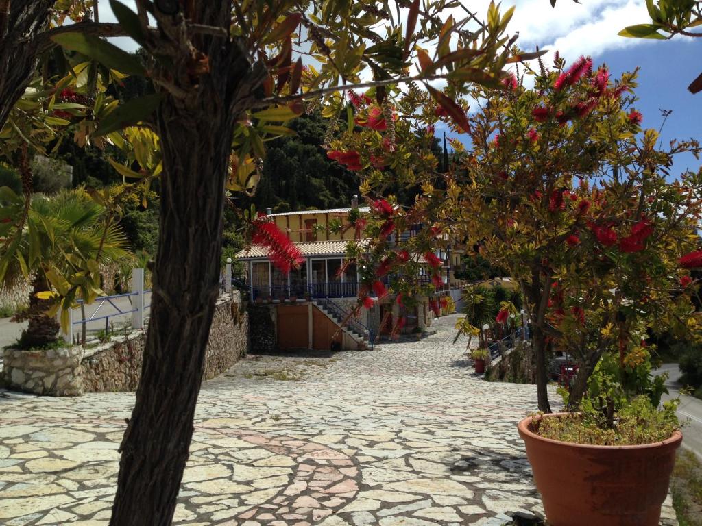 a stone walkway with trees and flowers in front of a building at Politia Hotel in Agios Nikitas