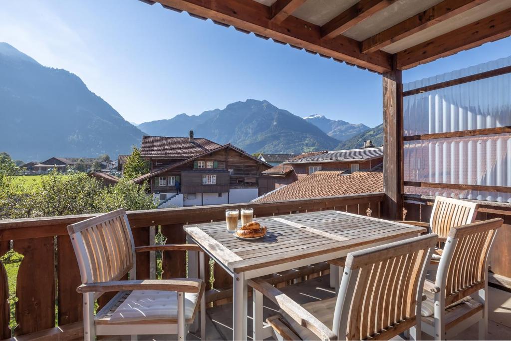 a wooden table and chairs on a balcony with mountains at Hasel in Interlaken