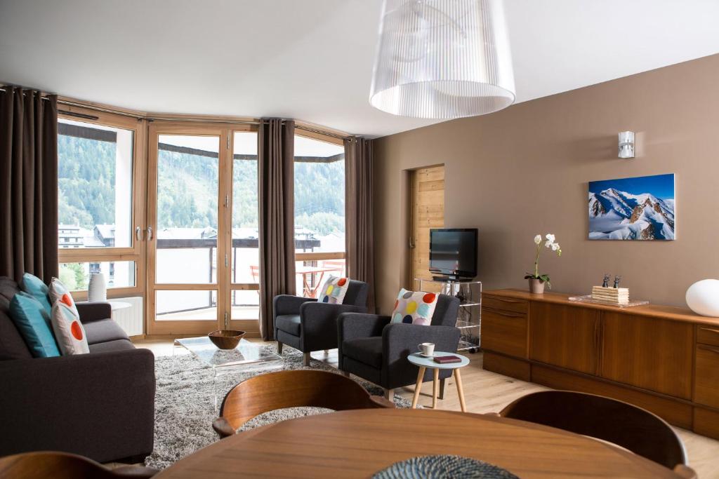 ein Wohnzimmer mit einem Tisch, Stühlen und einem TV in der Unterkunft Le Beausite C Apartment - Chamonix All Year in Chamonix-Mont-Blanc