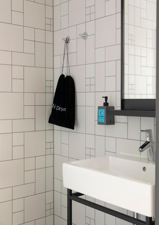 a white bathroom with a sink and a black bag at Comfort Hotel Xpress Youngstorget in Oslo