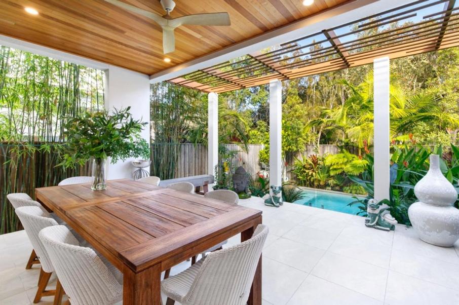 an outdoor dining room with a wooden table and chairs at Noosa Villas in Noosaville