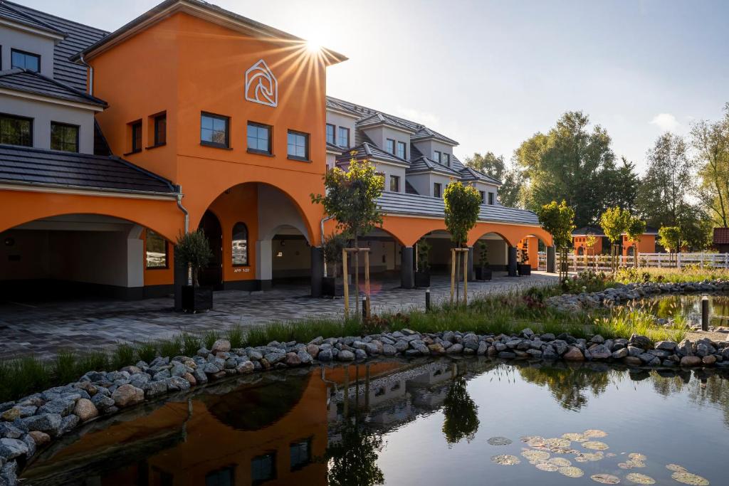 ein orangefarbenes Gebäude neben einem Wasserkörper in der Unterkunft Luxus Resort Rügen Residenz Kubitzer Bodden in Rambin