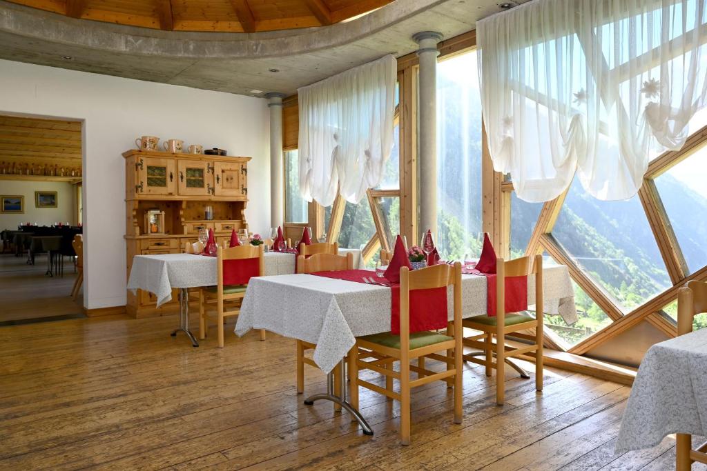 ein Esszimmer mit Tischen und Stühlen und einem großen Fenster in der Unterkunft Agriturismo Miravalle in Brusio