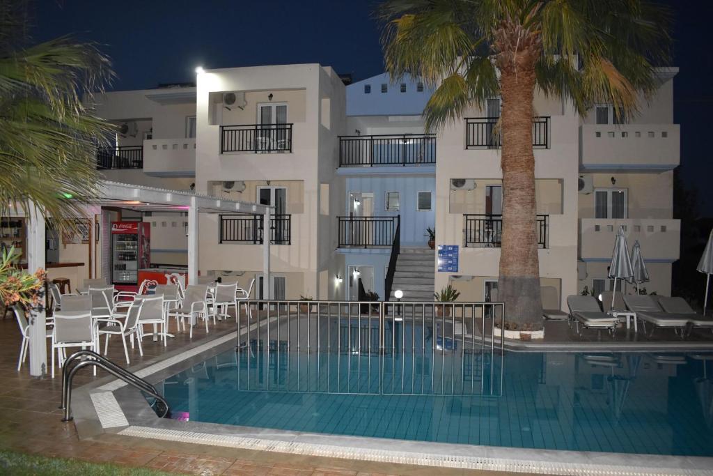 un hotel con piscina frente a un edificio en Sunshine Studios & Apartments, en Stalida