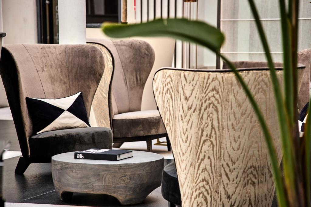 a living room with two chairs and a table with a book at H15 Boutique Hotel, Warsaw, a Member of Design Hotels in Warsaw