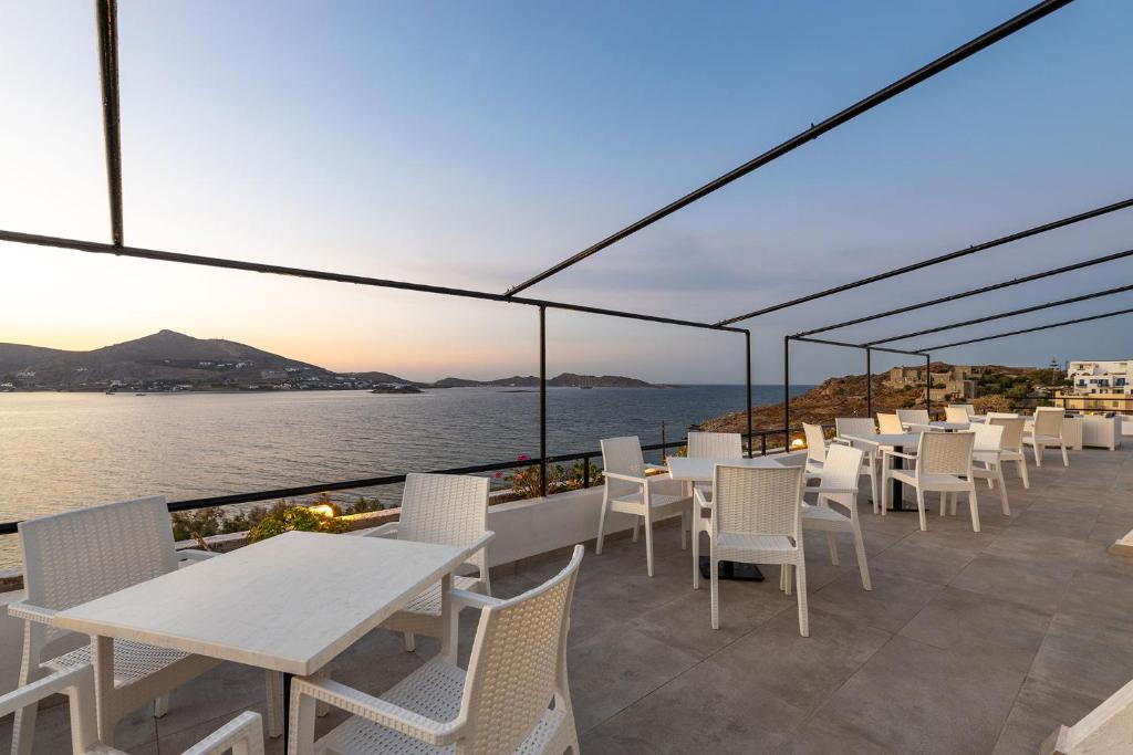 a row of tables and chairs on a patio with the ocean at Hippocampus Hotel in Naousa