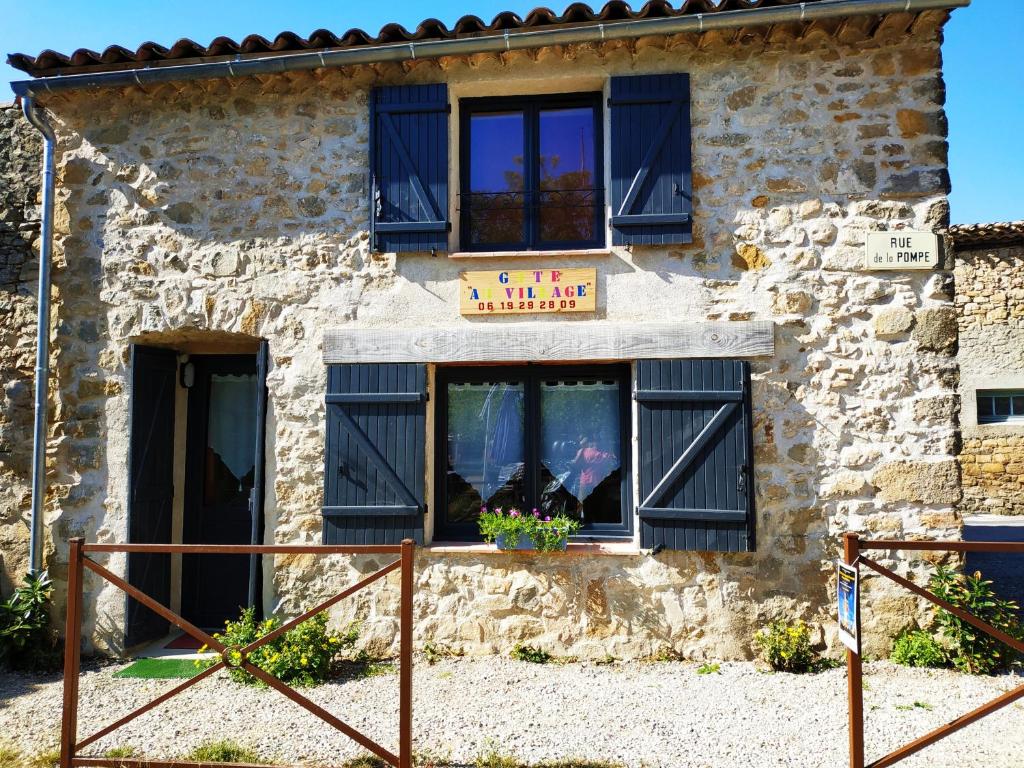 un edificio con ventanas negras y un cartel en él en Au Village, en Rennes-le-Château