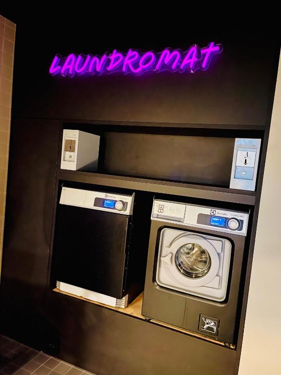 a washer and dryer in a room with a neon sign at Comfort Hotel Xpress Youngstorget in Oslo