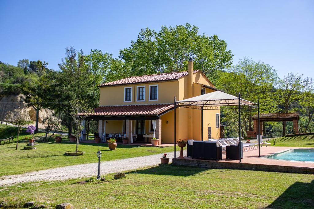 een klein geel huis met een zwembad in de tuin bij Podere Il Renaio in Legoli