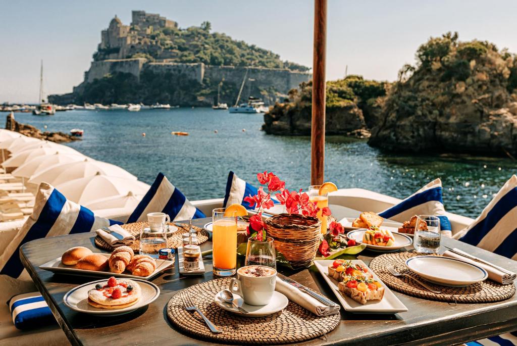 a table with food and a view of the water at Giardino Eden in Ischia
