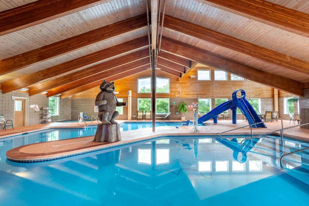 a indoor swimming pool with a pool slide and a house at AmericInn by Wyndham Wausau in Weston