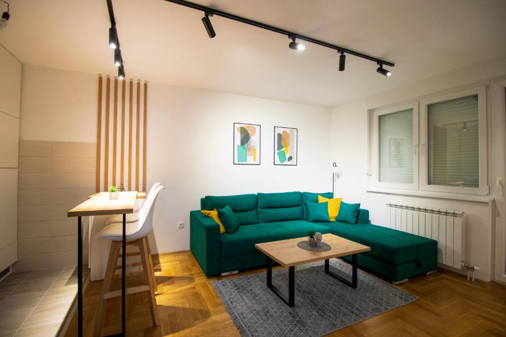 een woonkamer met een groene bank en een tafel bij M&A apartment in Lukavica