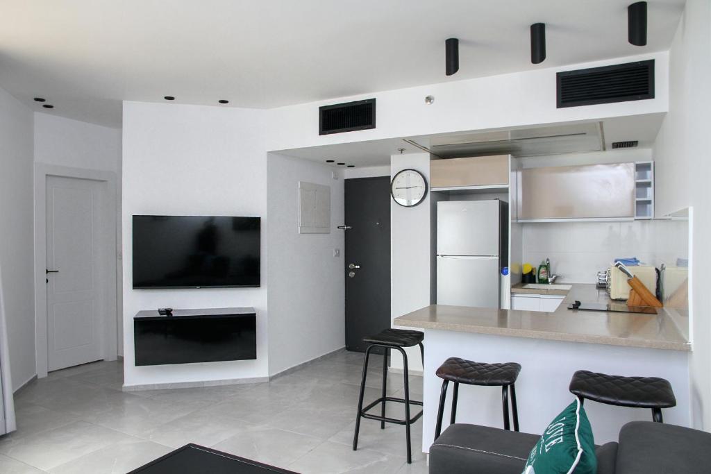 uma sala de estar com uma cozinha e um balcão com bancos em Apartments4you Leonardo 17 em Bat Yam