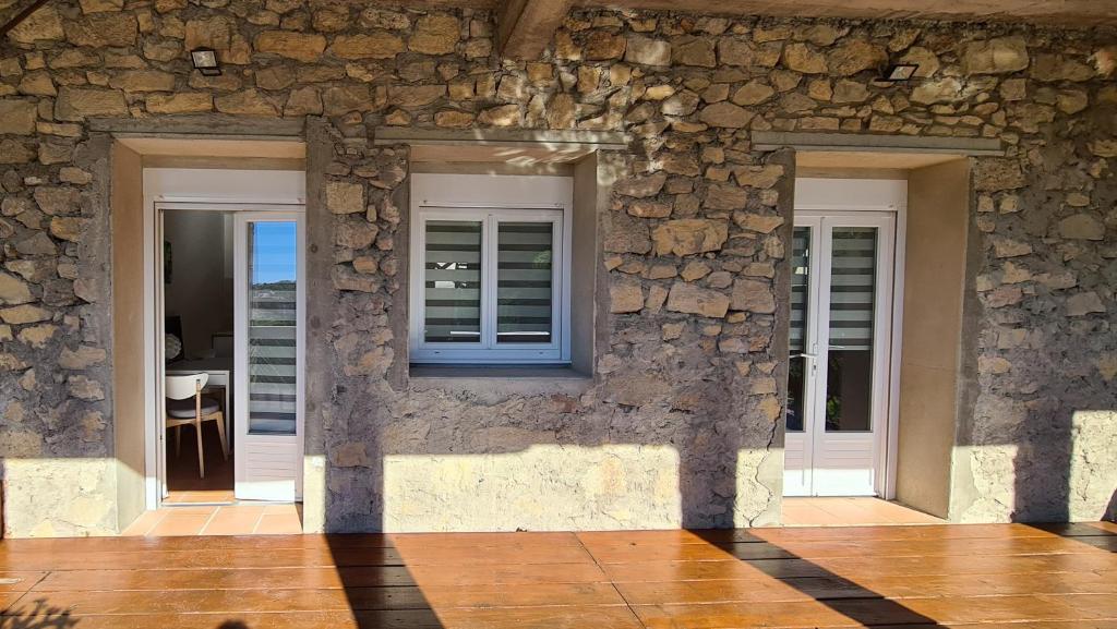 a stone building with a window and a stone wall at Campus Vivendi Studio in Montagnac