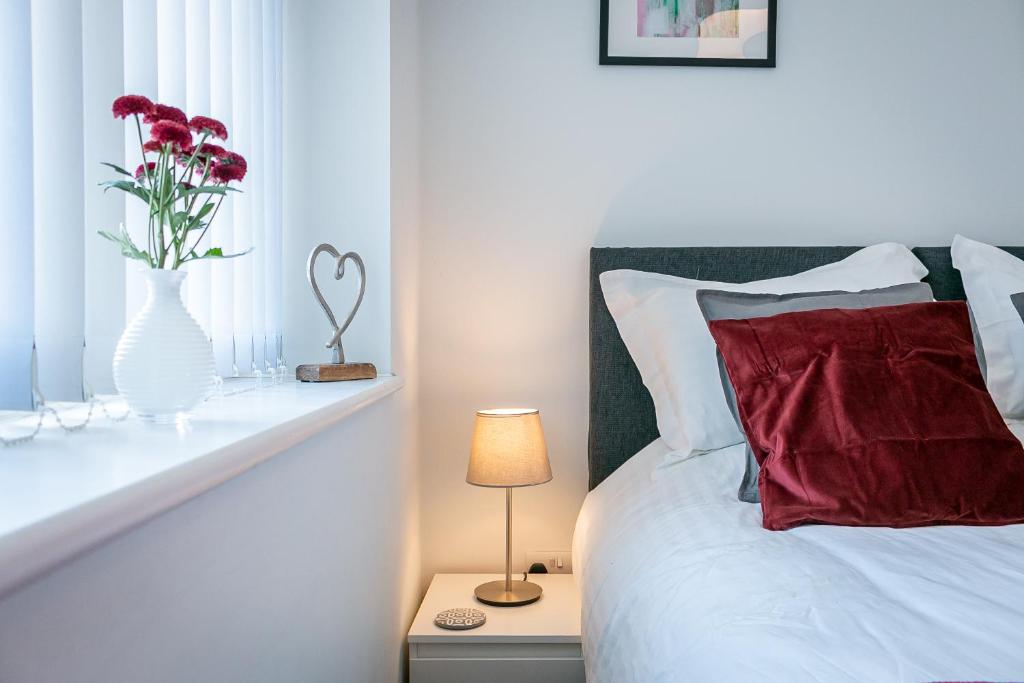 Executive Apartment Close to Station في هاتفيلد: غرفة نوم مع سرير مع مزهرية مع الزهور فيها