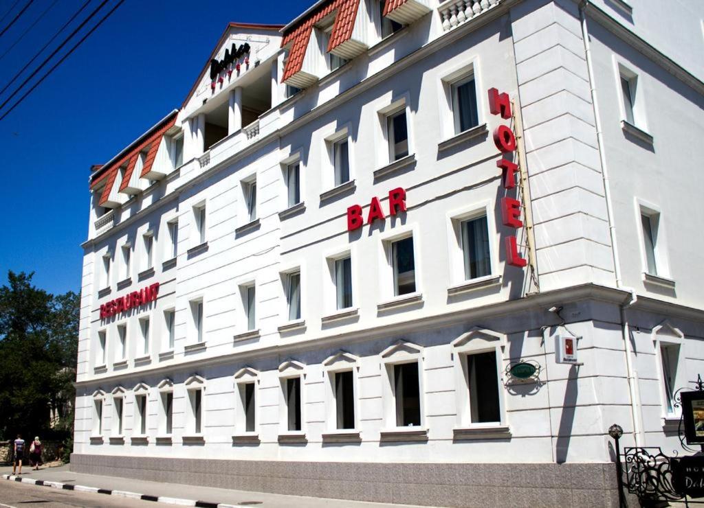 Biały budynek z czerwonym napisem w obiekcie Dakkar Hotel w mieście Bałakława