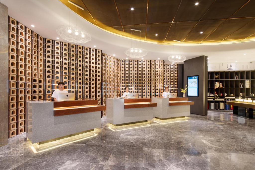 a lobby with two people sitting at desks in a building at Atour Hotel Yan'an Luyi Park in Yan'an