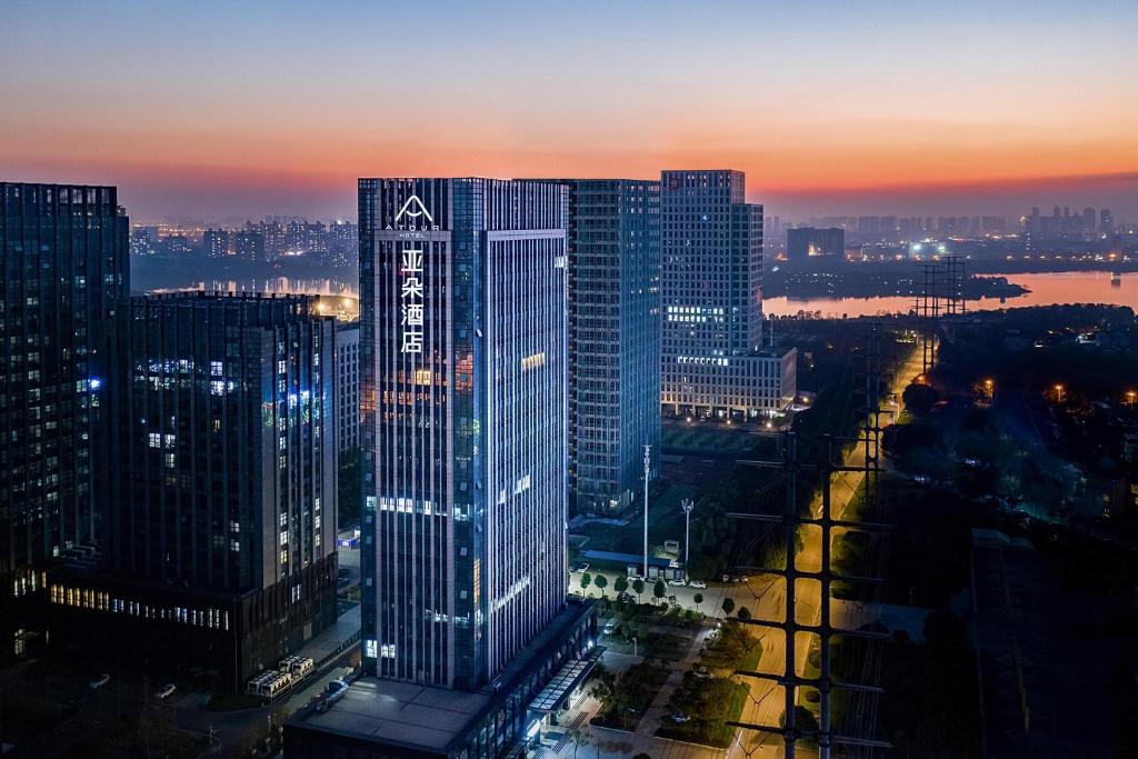 Atour Hotel Wuhan Jinyin Lake في ووهان: مبنى مرتفع مضاء في مدينة في الليل