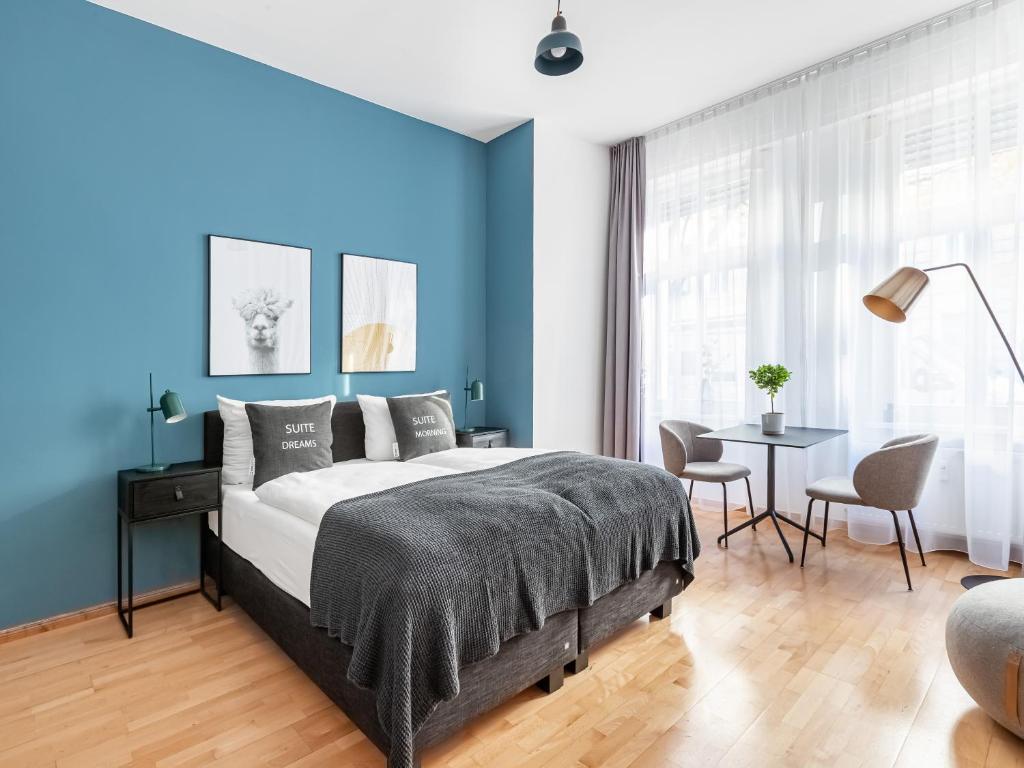 ベルリンにあるlimehome Berlin Malmöer Straßeの青い壁のベッドルーム1室、ベッド1台、テーブルが備わります。