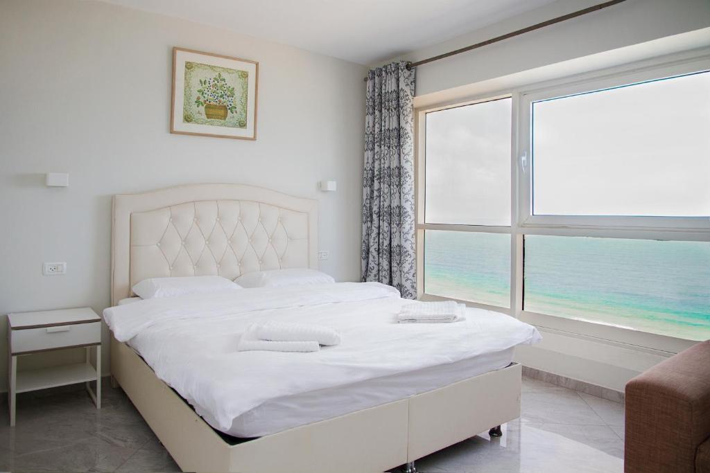 a bedroom with a bed and a large window at Apartments4you Leonardo 11 in Bat Yam