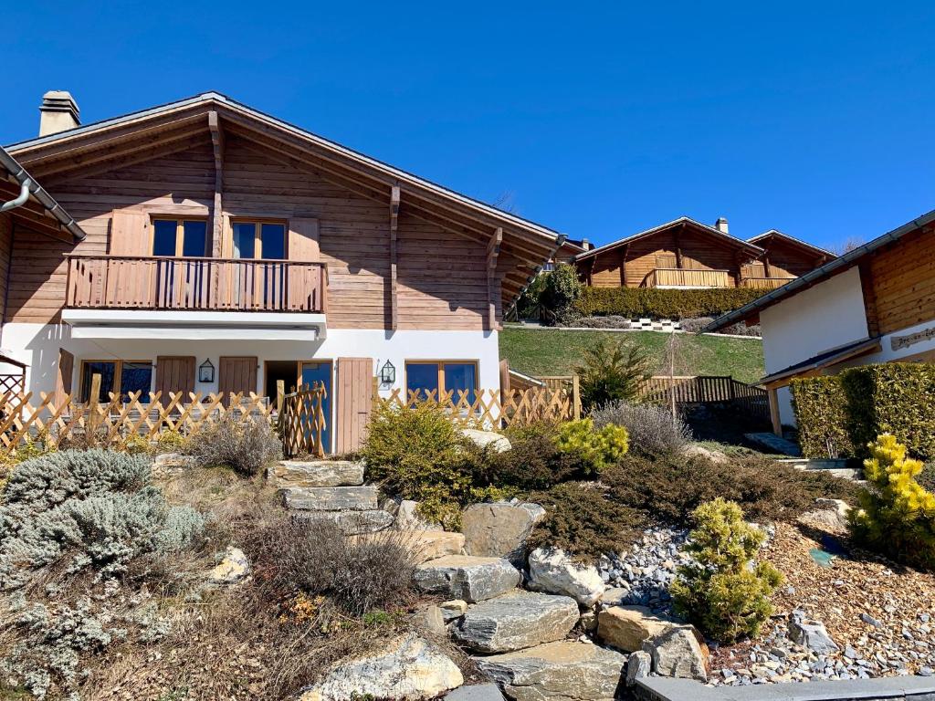 a house with a balcony and a yard with rocks at K2 Chalet in Crans-Montana