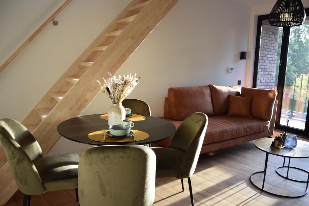 - un salon avec une table, des chaises et un canapé dans l'établissement CaCeLe Raveelzicht, à Zulte