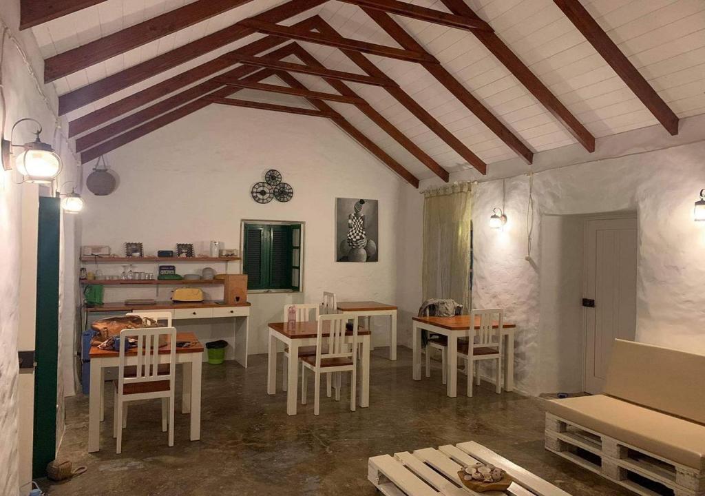 Nos Kasa Povoaçao Velha في Cabeçadas: غرفة معيشة مع طاولات وكراسي في غرفة ذات سقف