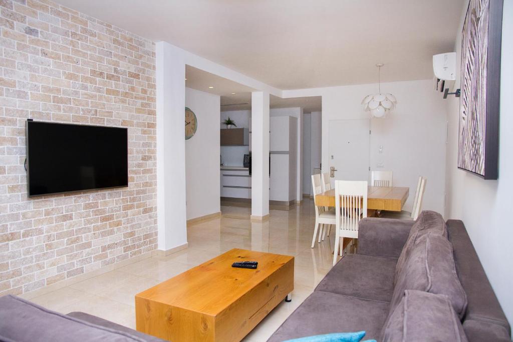a living room with a couch and a brick wall at Apartments4you Etsel in Bat Yam