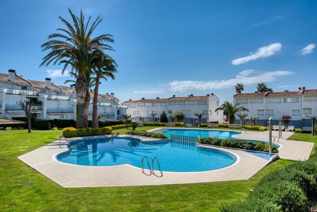 uma piscina num resort com palmeiras e edifícios em Big Villa Sagaró em S'agaró
