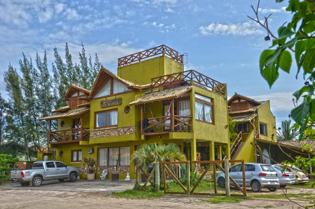 a yellow house with cars parked in front of it at Pousada Pé na Areia in Garopaba