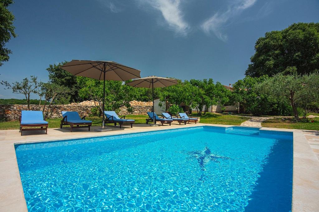 a swimming pool with chairs and umbrellas in a yard at Villa Altura in Valtura