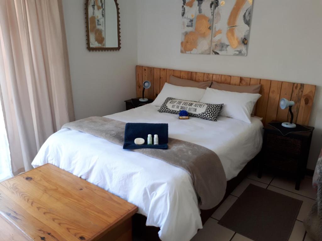 a bedroom with a white bed with a wooden headboard at La Casa on Bashee in Boksburg
