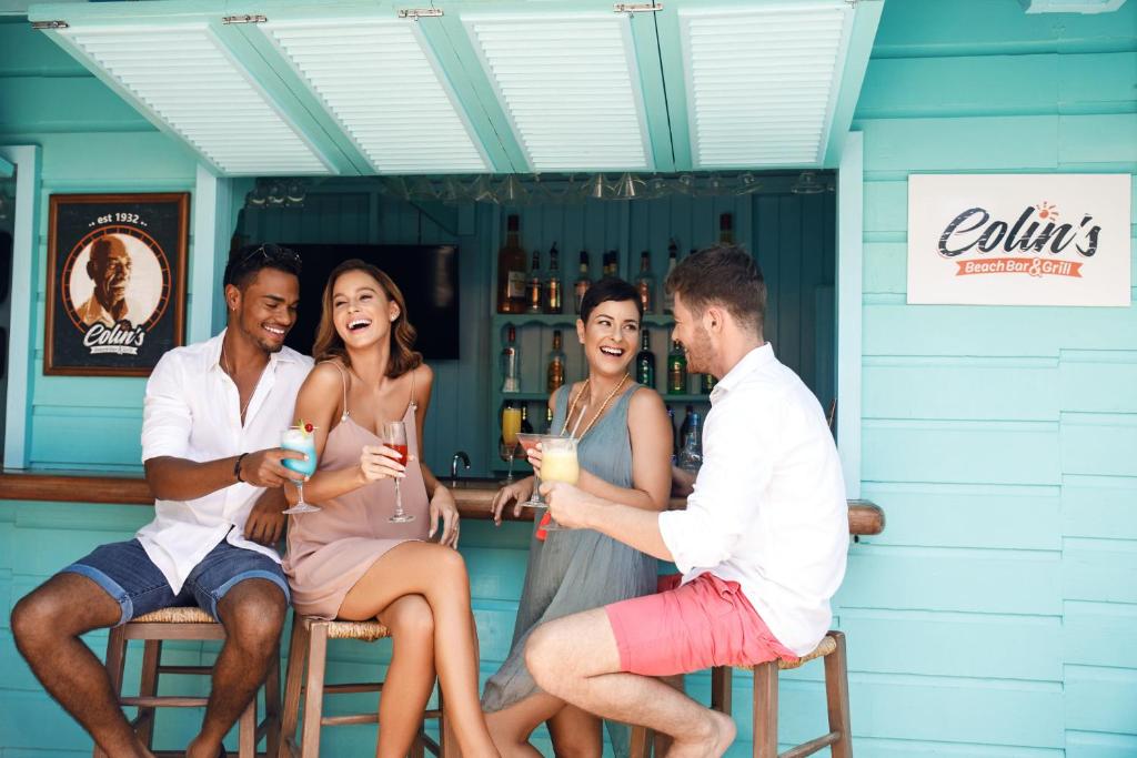 a group of people sitting around a bar with drinks at Sugar Bay Barbados - All Inclusive in Bridgetown