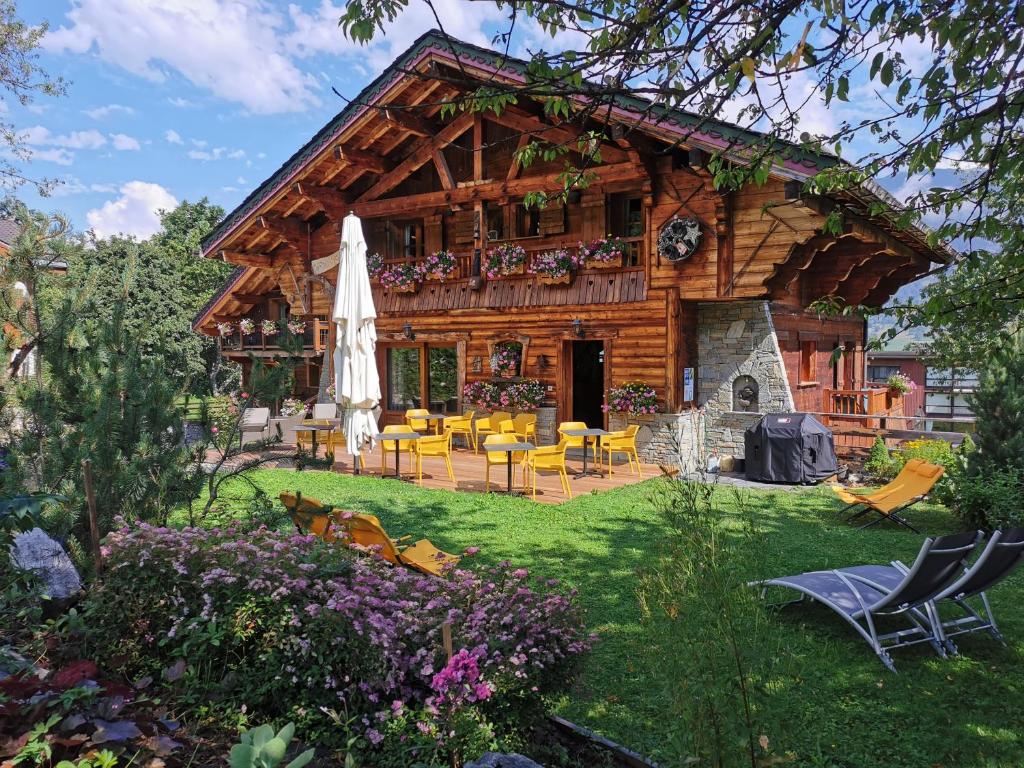 um chalé de madeira com um pátio, mesas e cadeiras em Chalet Jardin d'Angèle Chambres d'hôtes em Courchevel