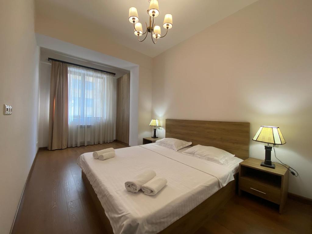 a bedroom with a large bed with two towels on it at Byuzand Yerevan Apartment in Yerevan