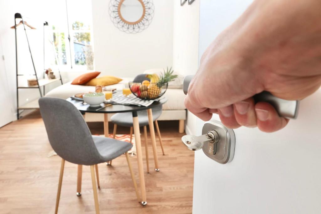 una mano que abre la puerta de una habitación con mesa y sillas en Napoléon Gare 5 STUDIO 1er Etage ByLocly, en Pontivy