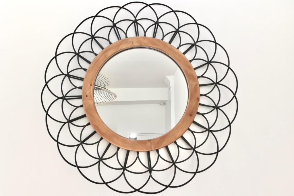 a circular mirror with a wooden frame in the shape of a spiral at Napoléon Gare 5 STUDIO 1er Etage ByLocly in Pontivy