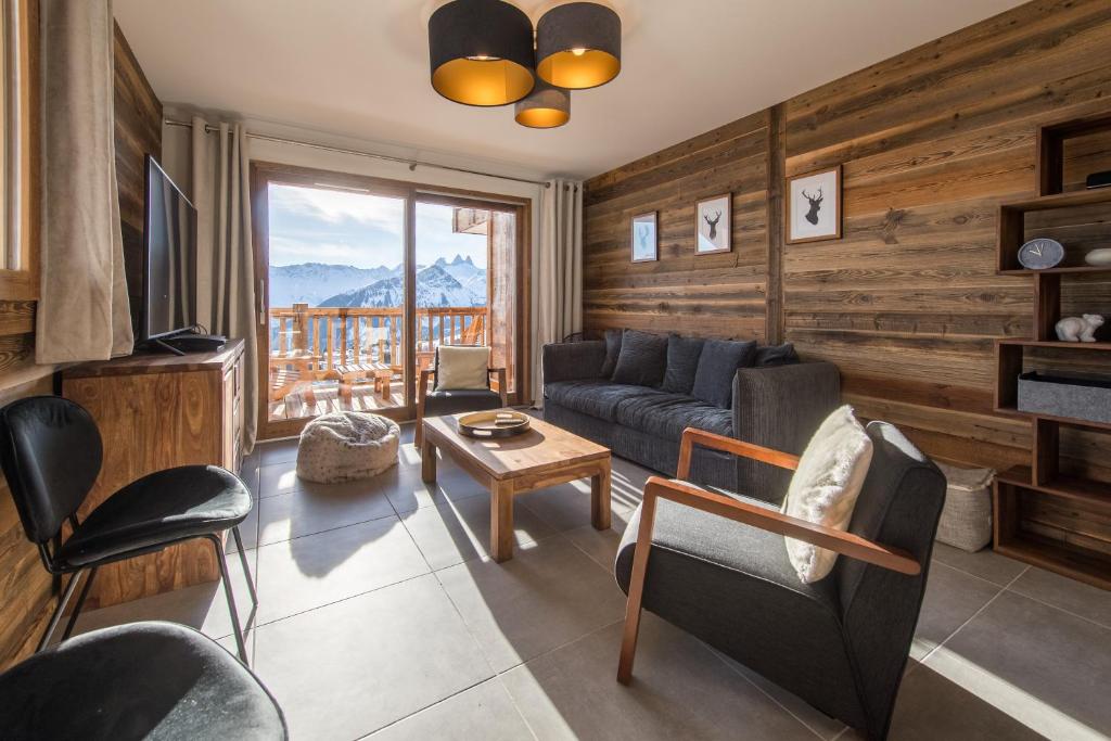 a living room with a couch and a television at ODYSSEE A201 Vaste appartement en vieux bois sur les pistes, vue panoramique in La Toussuire