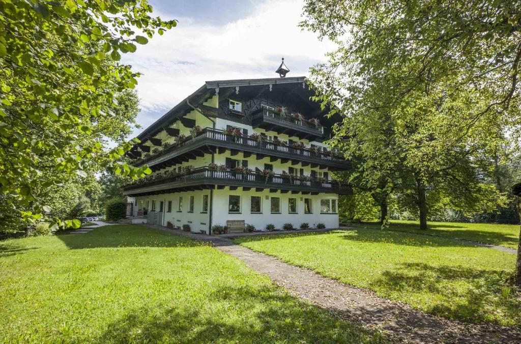 ein großes weißes Gebäude in einem Park mit Bäumen in der Unterkunft Haus Auerbach in Oberaudorf