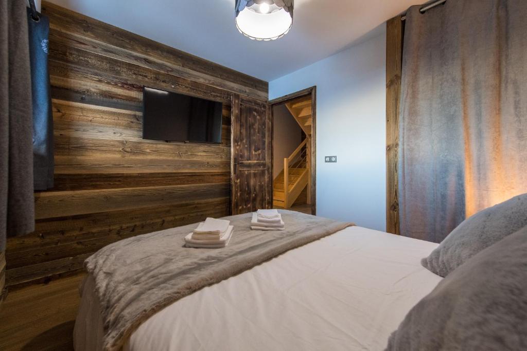a bedroom with a bed with a wooden wall at ODYSSEE A201 Vaste appartement en vieux bois sur les pistes, vue panoramique in La Toussuire