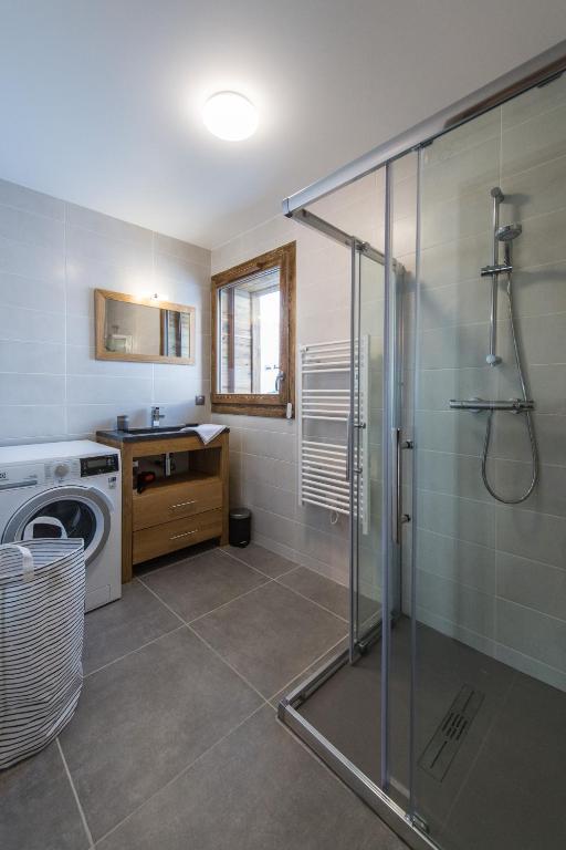 a bathroom with a shower and a washing machine at ODYSSEE A201 Vaste appartement en vieux bois sur les pistes, vue panoramique in La Toussuire