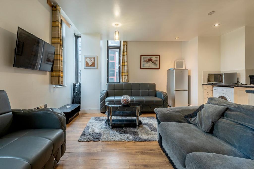 a living room with two couches and a kitchen at Lever St Central in Manchester